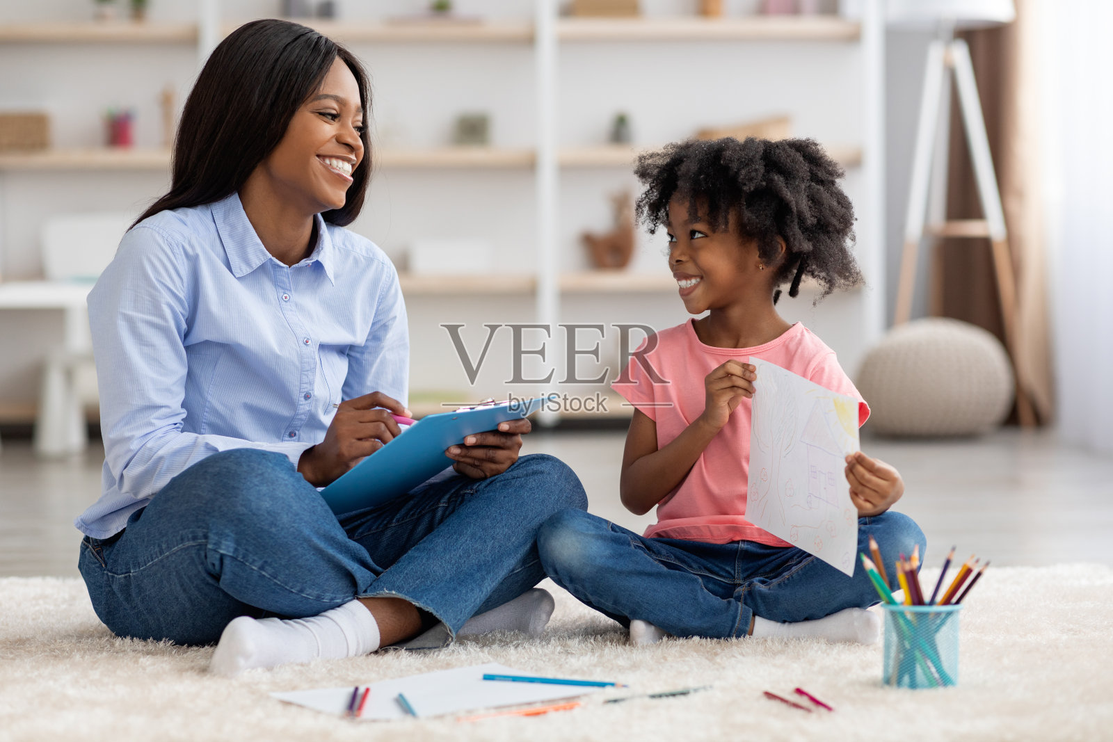 卷毛的非裔美国小女孩给心理学家看她的画照片摄影图片