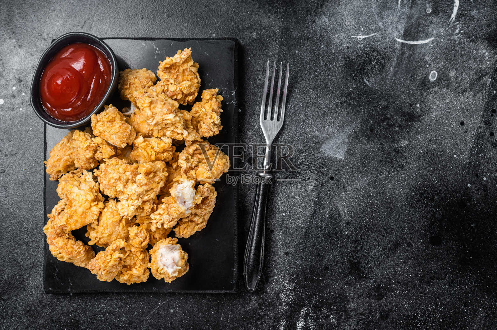 裹着面包屑的脆炸鸡块，配上番茄酱。黑色背景。前视图。本空间照片摄影图片