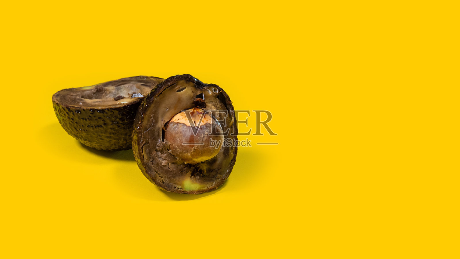 非常烂的鳄梨黄色背景，坏的熟过头的热带水果。照片摄影图片