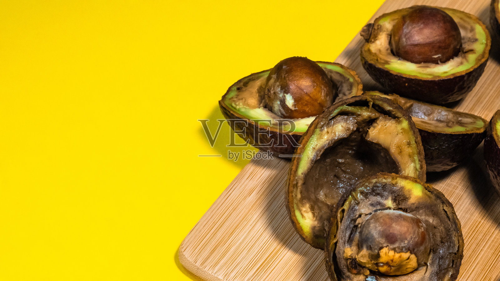 腐烂的鳄梨黄色背景。照片摄影图片