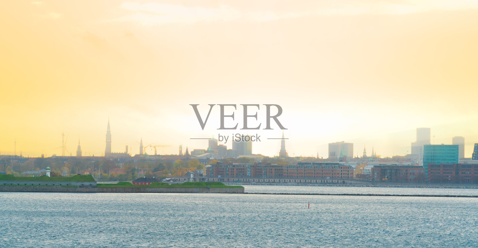 从海边看到的温暖的秋日夕阳，哥本哈根城市的天际线。照片摄影图片