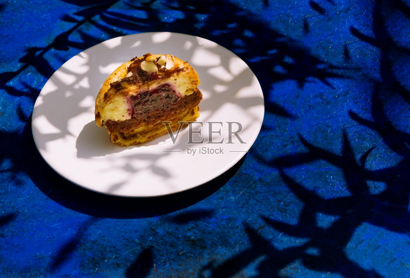 小尺寸的松饼，在明亮的阳光下以蓝色为背景的覆盆子。夏天的糕点。糖果博客，咖啡馆和餐厅的横幅。菜单的糖果。诱人的报价照片摄影图片