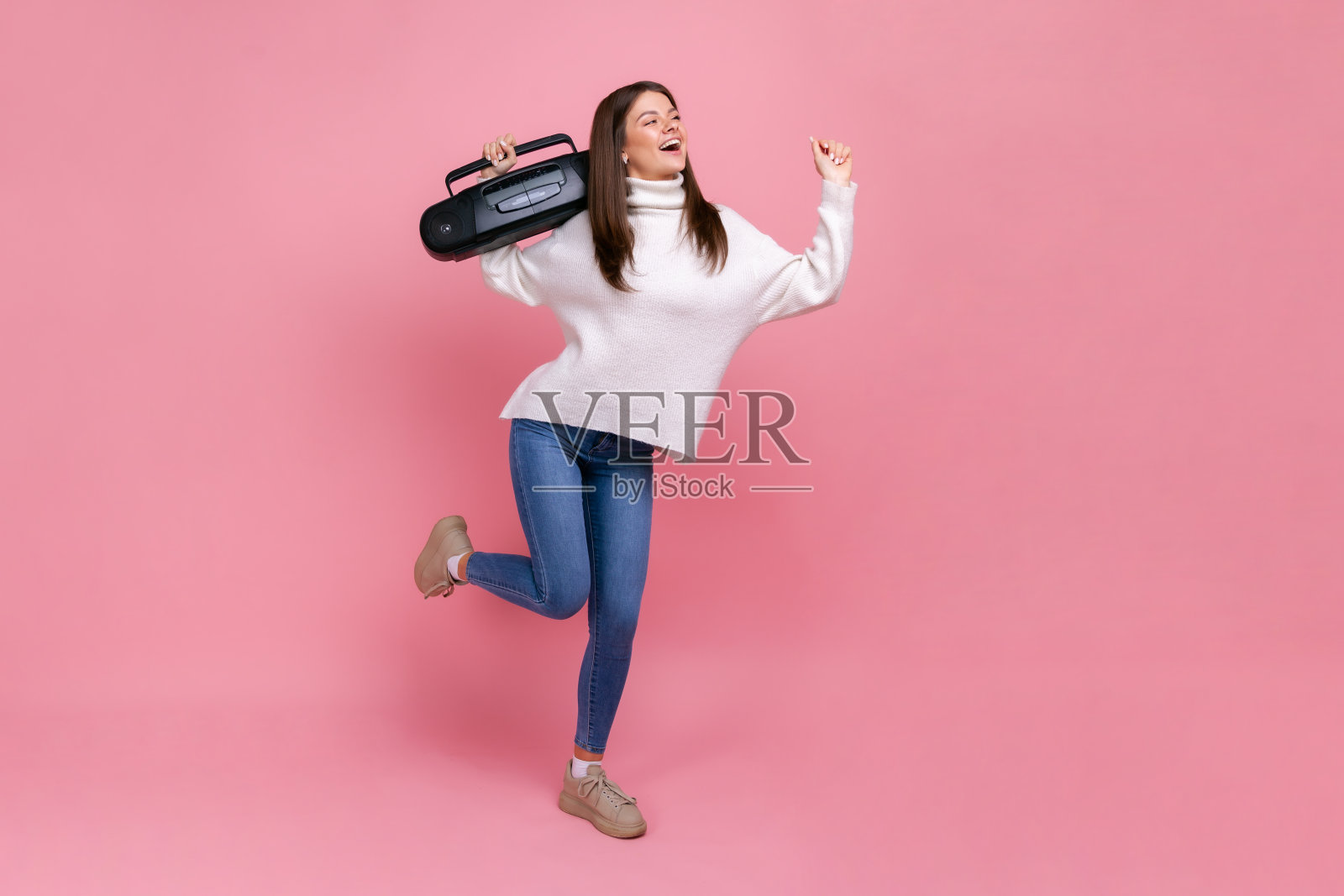 正面女性的全身肖像站在录音机，听歌曲和跳舞。照片摄影图片