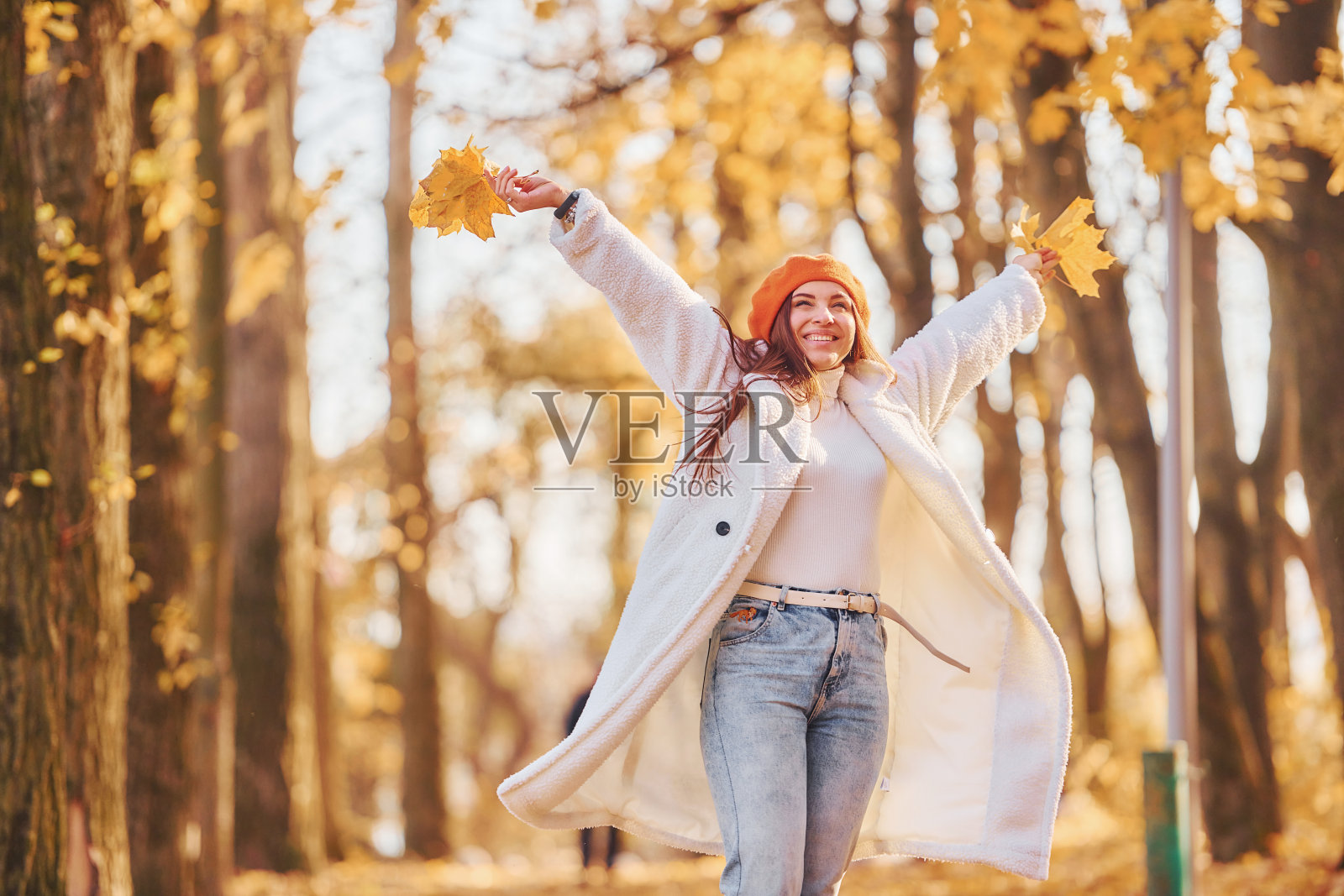 红色贝雷帽。穿着白大褂的女人在秋天的公园里玩耍照片摄影图片