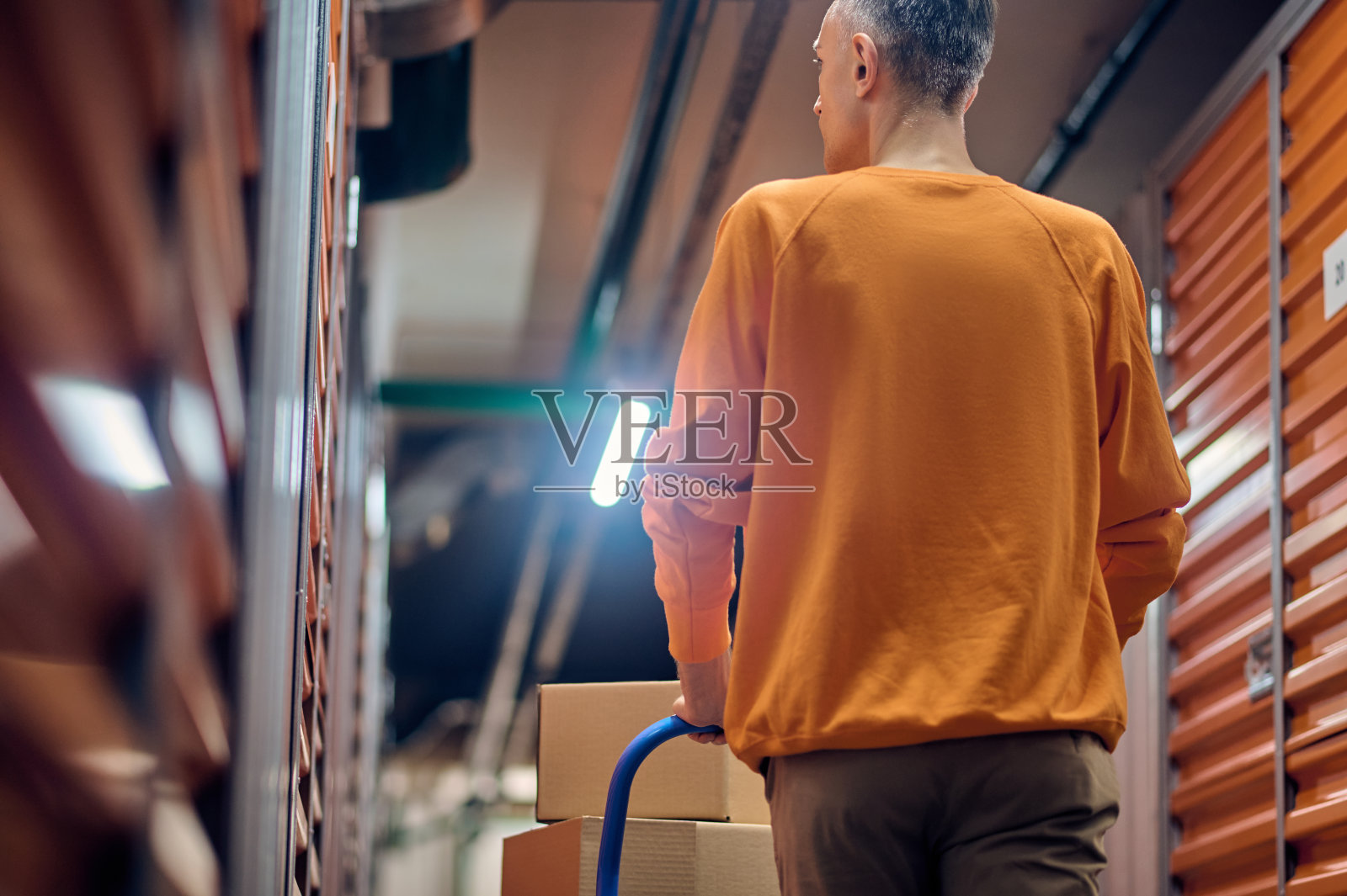 仓库员工推着平台小车沿集装箱前进照片摄影图片