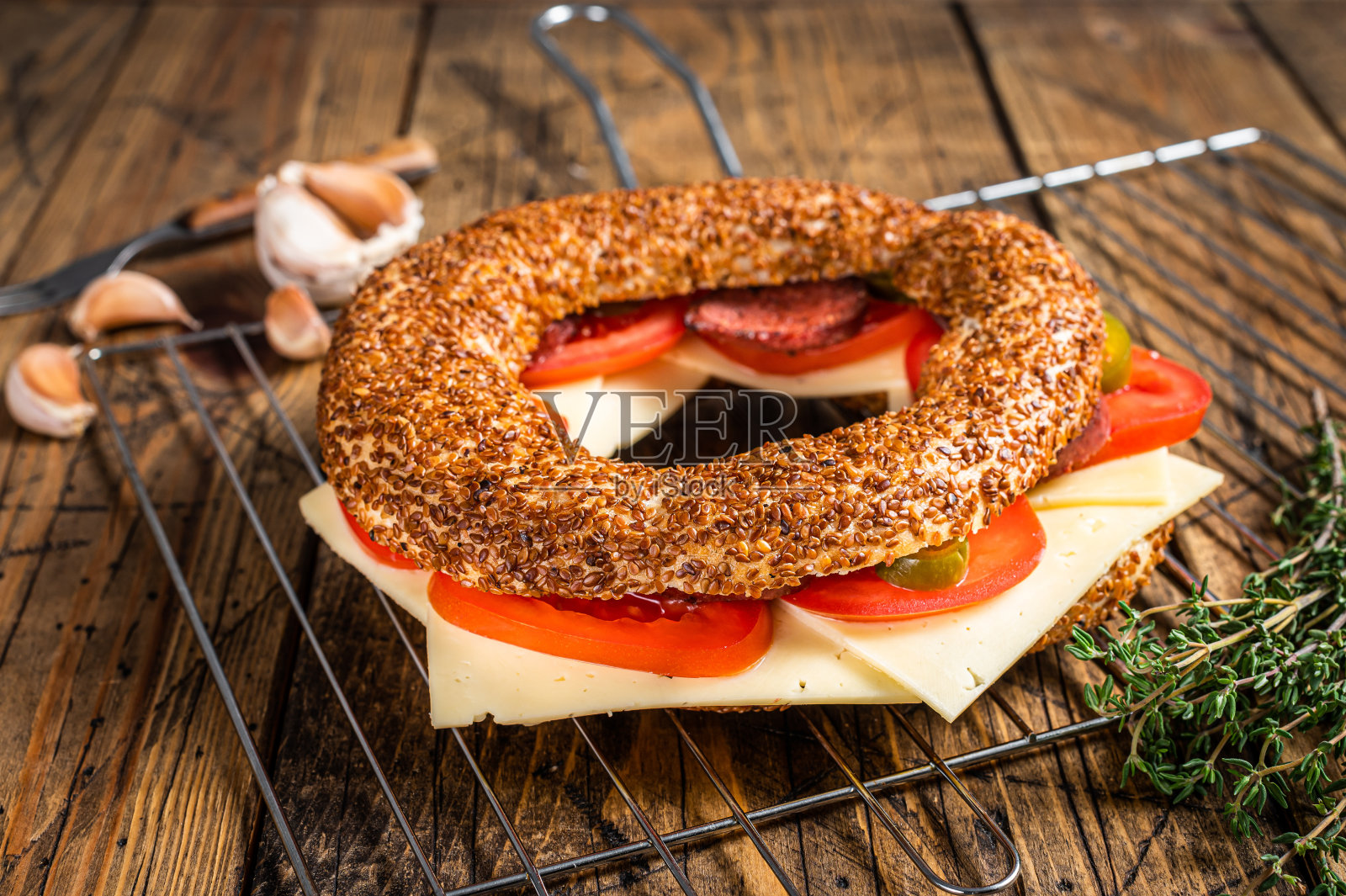 百吉饼三明治配生菜，番茄，黄奶酪和香肠。木制背景。俯视图照片摄影图片