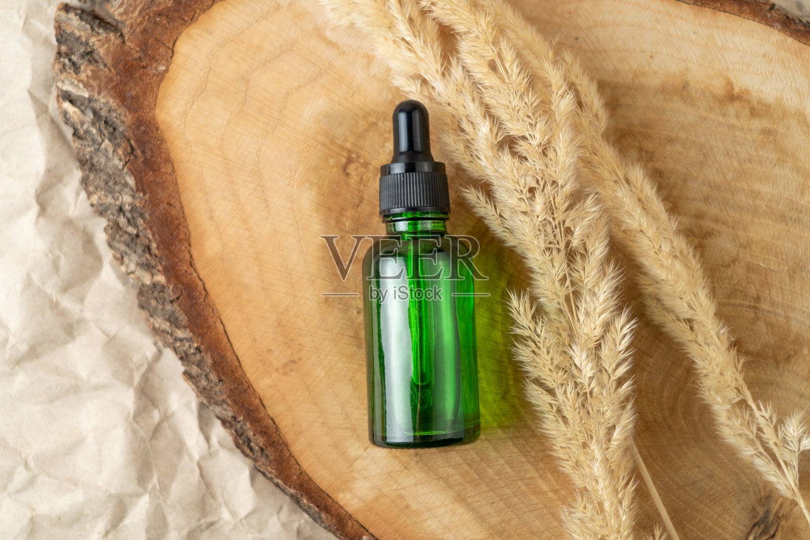 一个绿色的滴液瓶，里面装着血清或天然油，放在一个木制的托盘上照片摄影图片