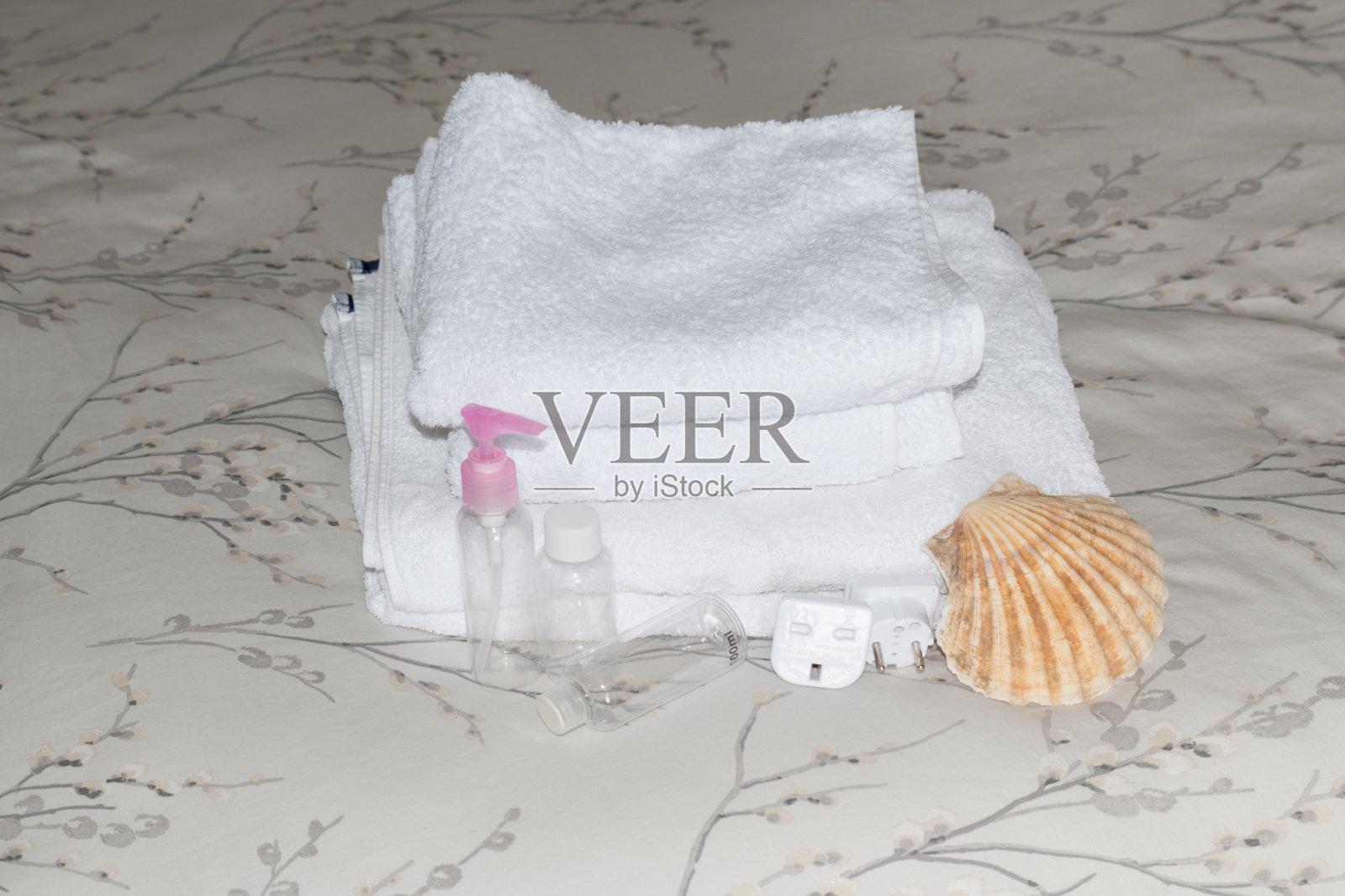 白色毛巾包的特写，整齐的堆叠，干净的100毫升塑料瓶，适配器和白色的浴海绵照片摄影图片