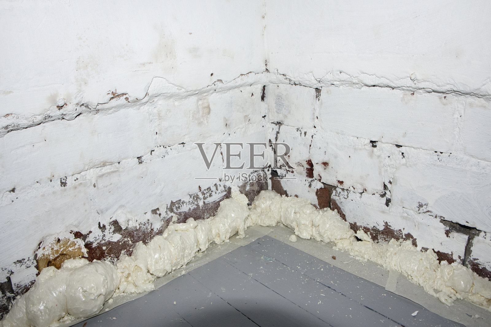 膨胀泡沫在室内砖墙底部-聚氨酯泡沫。照片摄影图片