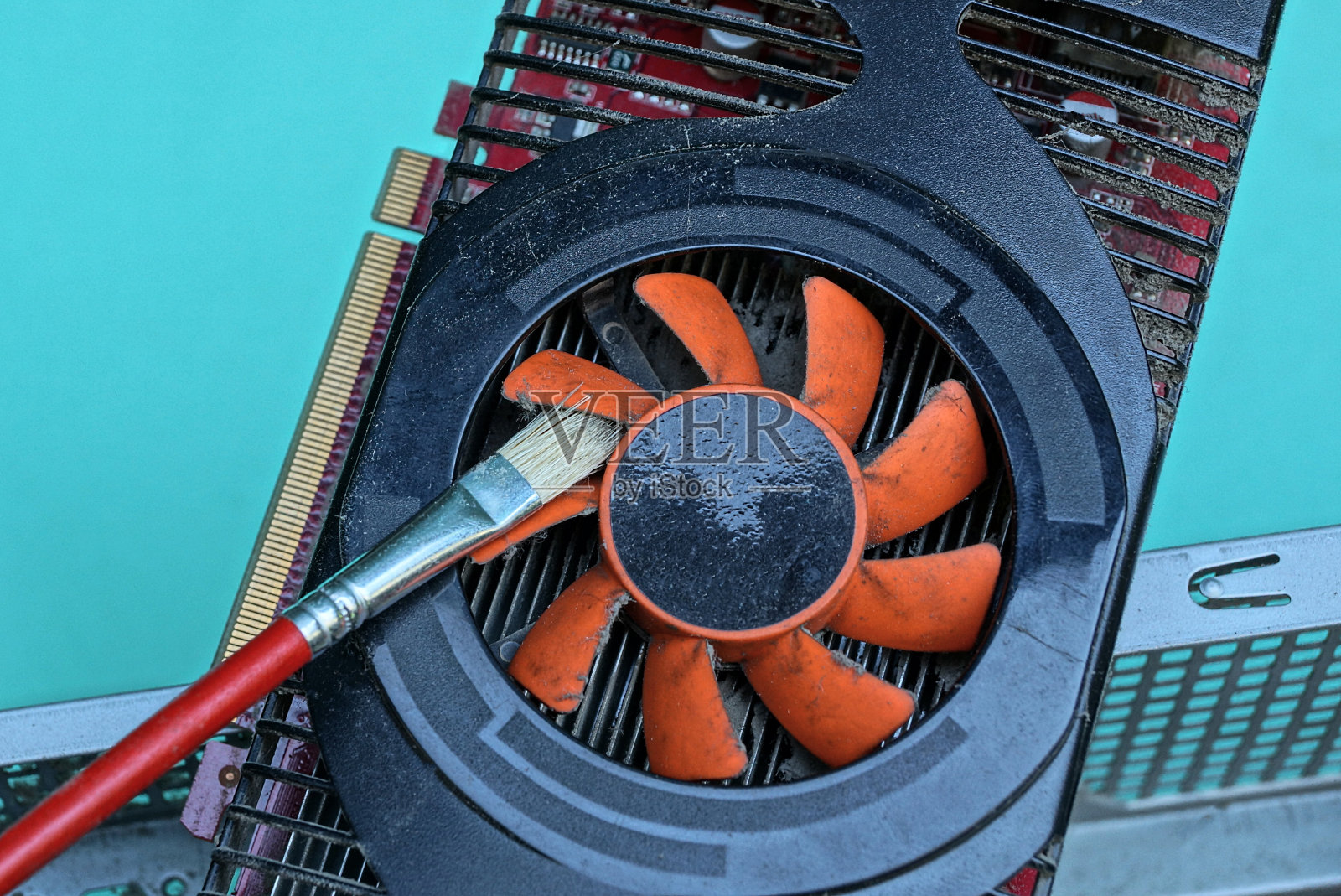 长刷子可以清除显卡上红色塑料风扇上的灰尘照片摄影图片