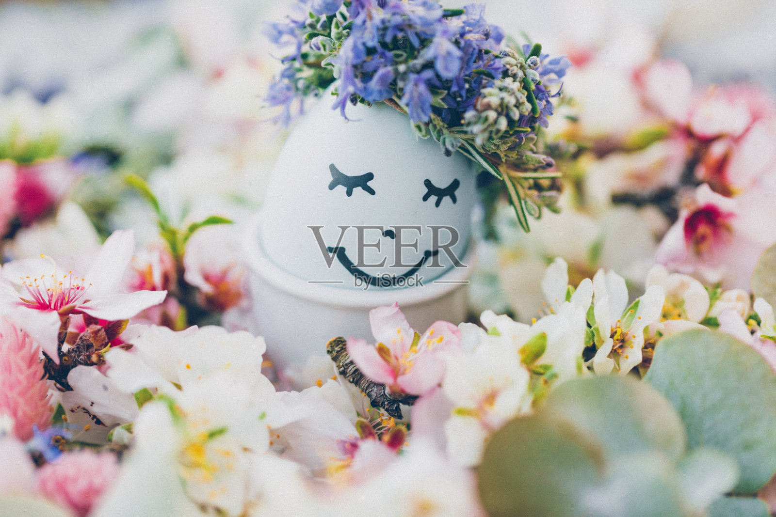 带着微笑和沉睡的复活节彩蛋，花环是迷迭香，周围是杏花和其他干花。照片摄影图片