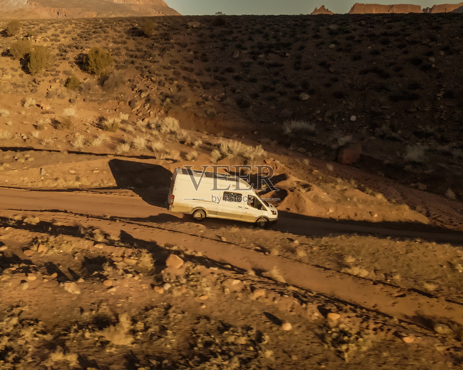 白色改装露营车行驶在犹他州摩押附近的科罗拉多西南部沙漠山区的一条土路上照片摄影图片