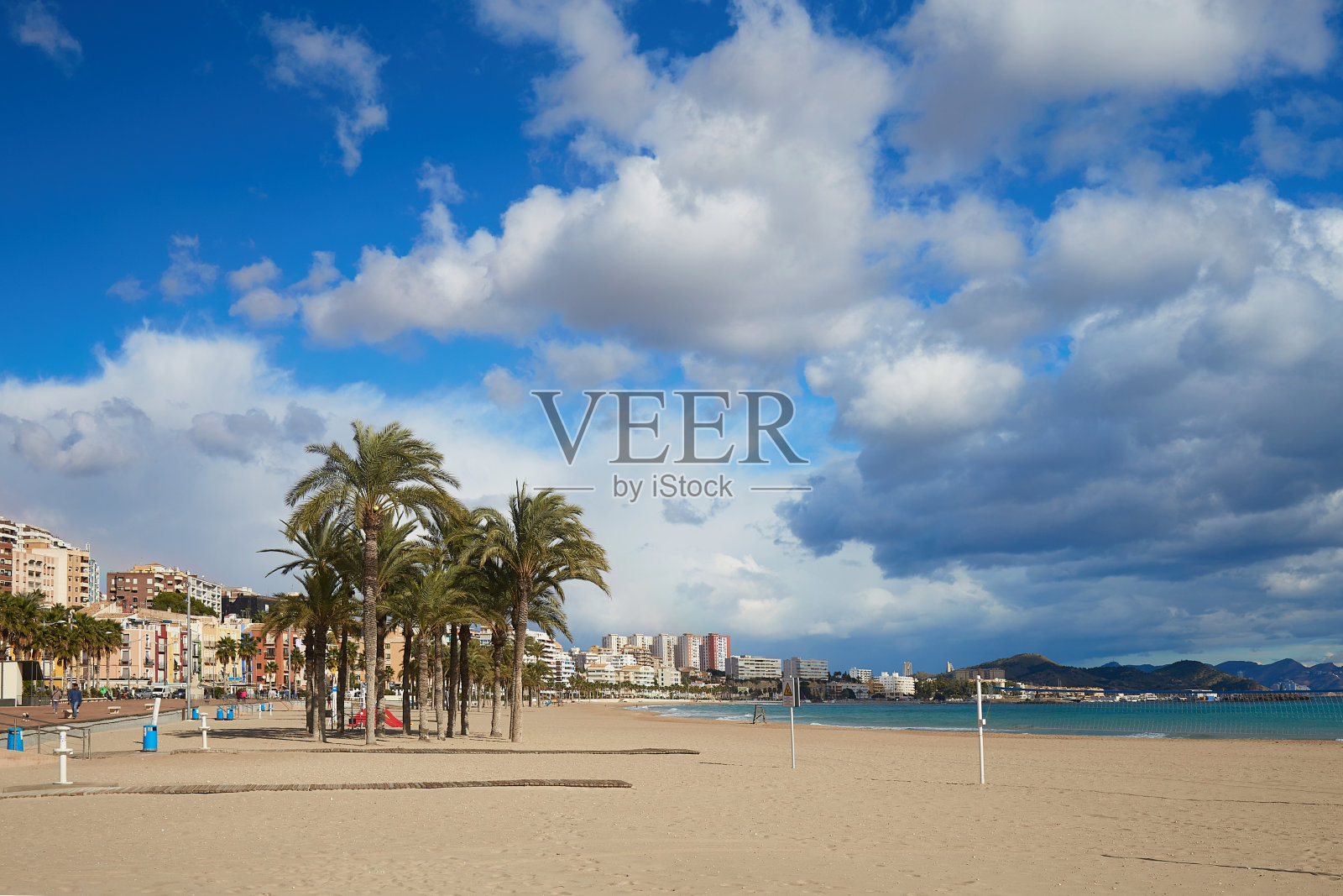 西班牙，比利亚茹瓦约萨，沙滩上，沿着长廊的棕榈树，五颜六色的房子和天空中引人注目的云彩照片摄影图片