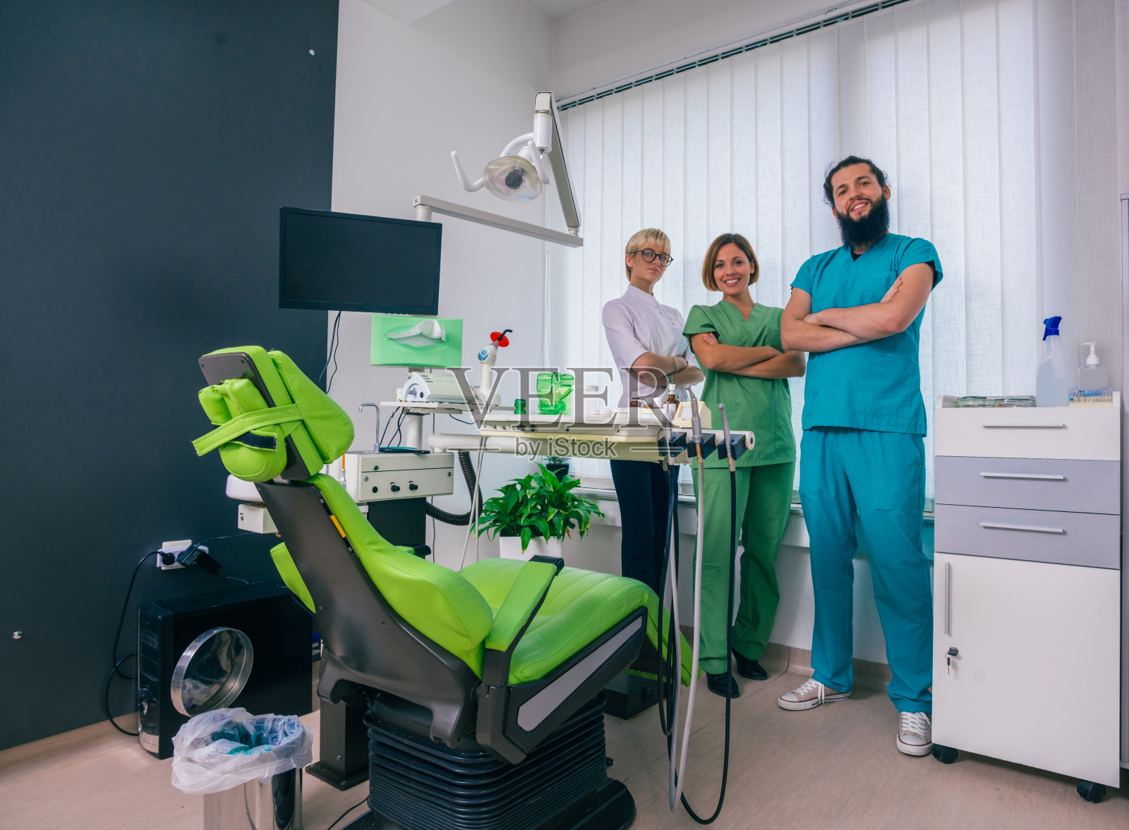 三个快乐的牙医自豪地在牙科办公室摆姿势照片摄影图片