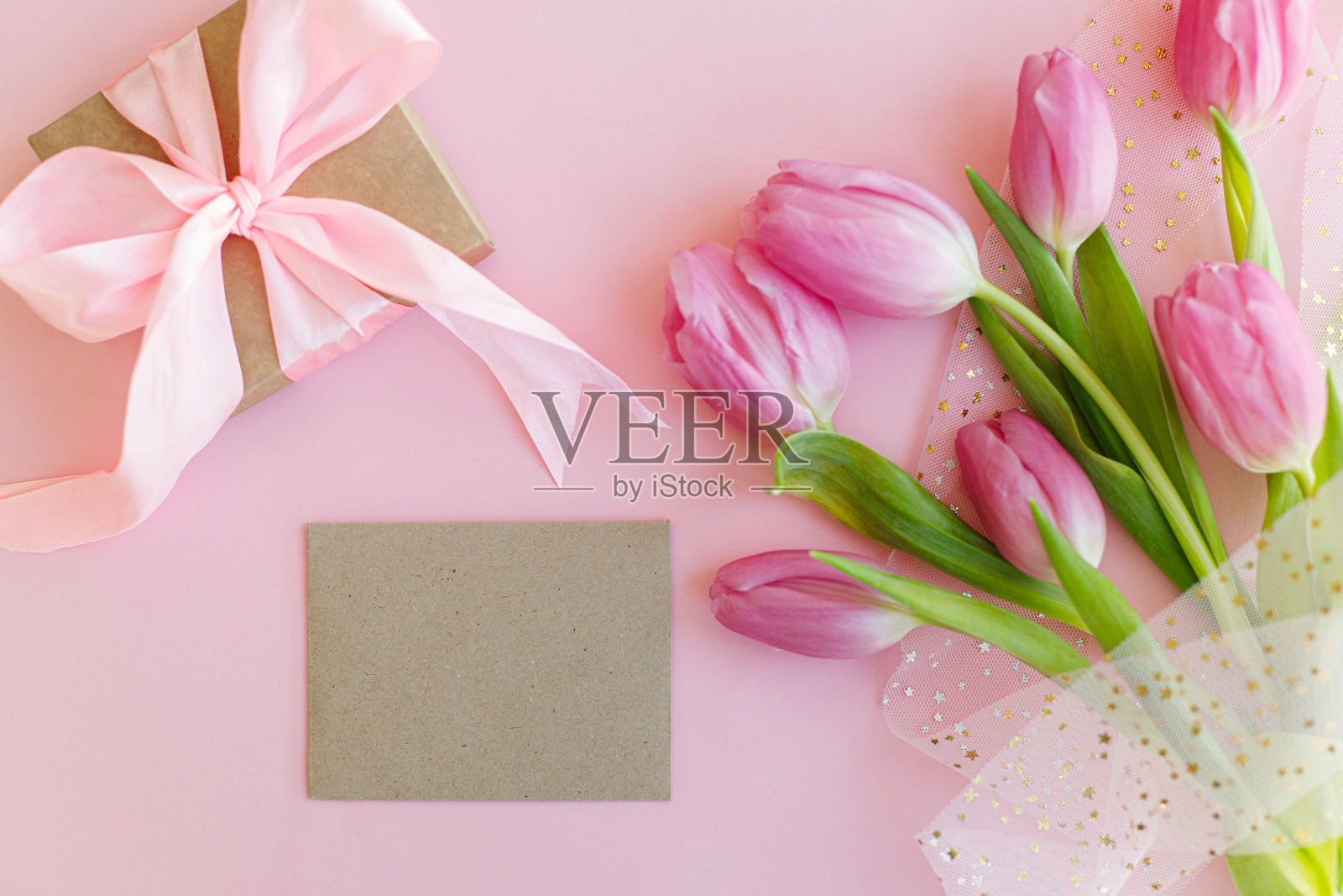 空贺卡，粉红色的郁金香花束和礼品盒平躺在粉红色的背景上。带有文本空间的贺卡模板。快乐的女子。快乐的母亲节。3月8日照片摄影图片