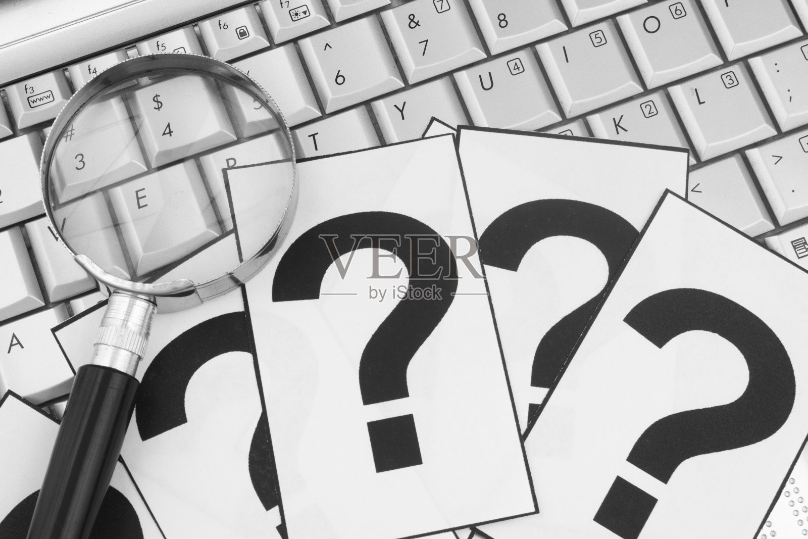 放大镜和笔记本电脑键盘上的问号。照片摄影图片