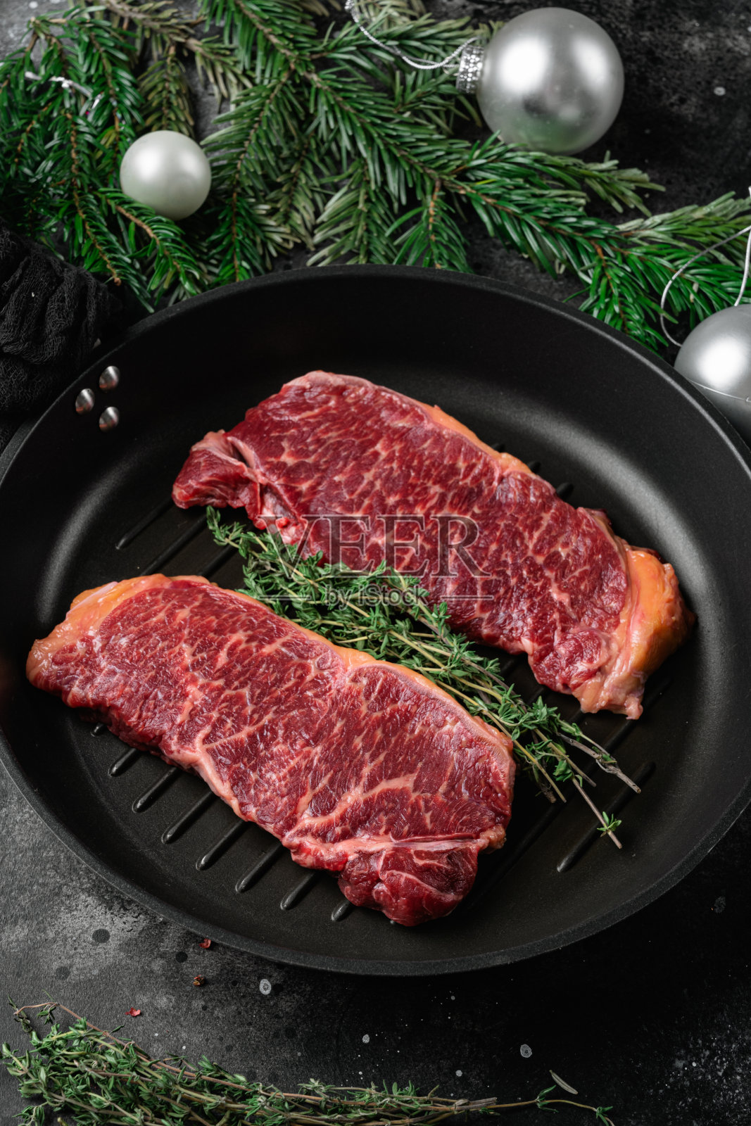 生纽约牛排与圣诞树装饰，在黑色的黑色石头桌子背景照片摄影图片
