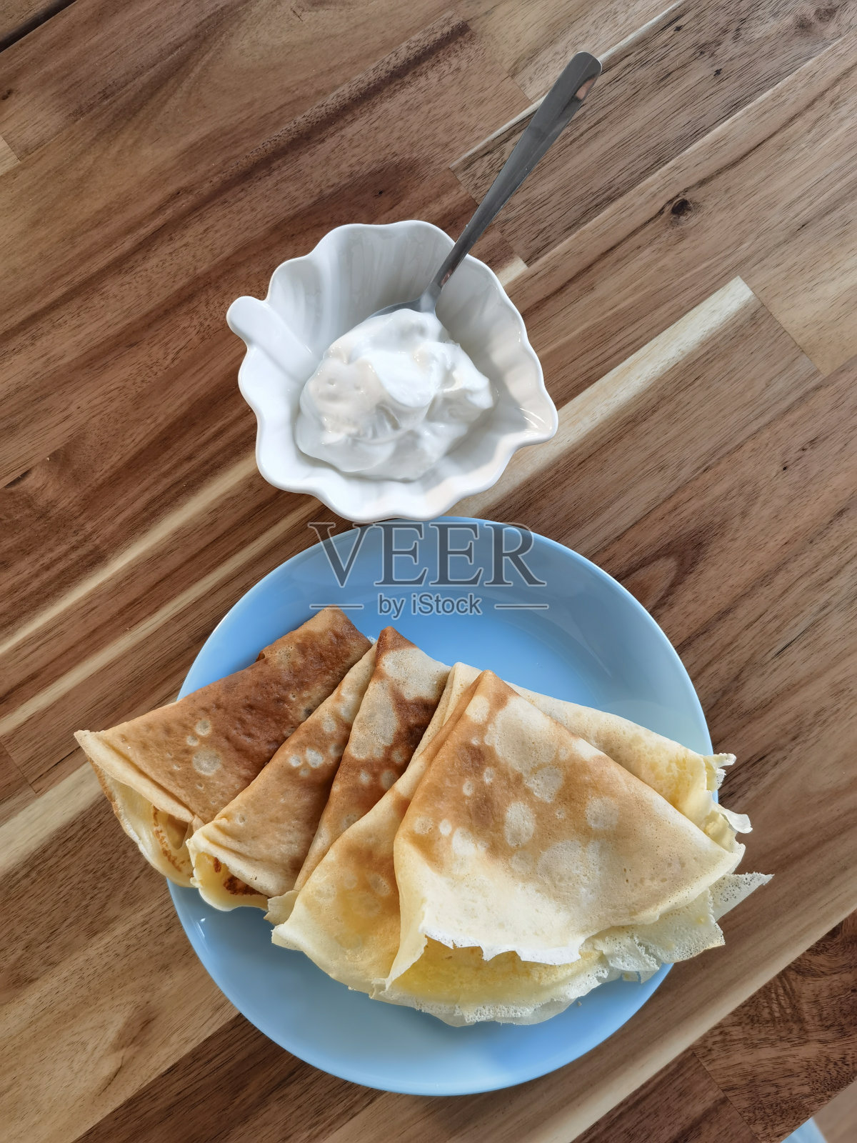 木桌上的俄罗斯煎饼配酸奶油。传统的俄罗斯乌克兰食物。象征宝宝，送走冬天。真实的斯拉夫早餐照片摄影图片