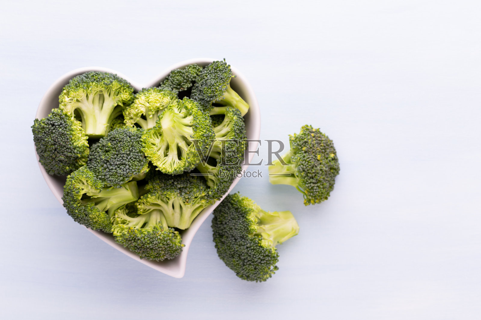 新鲜的花椰菜放在一个木制背景的心形碗里。照片摄影图片