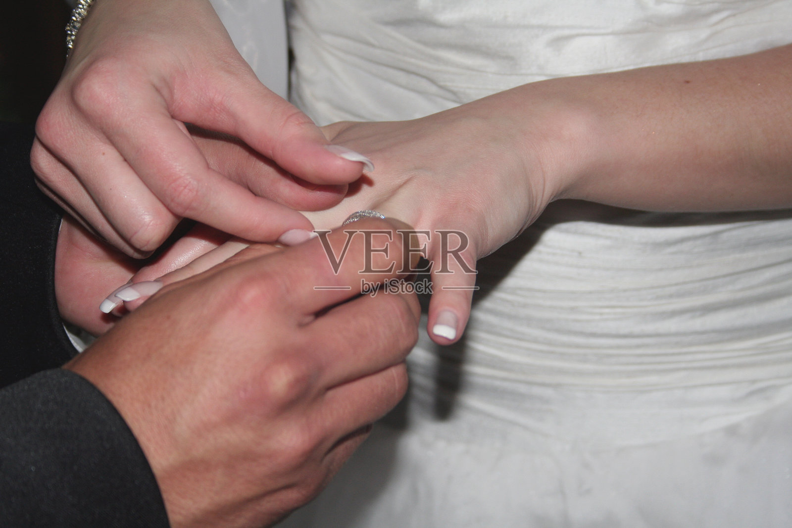 新郎把结婚戒指戴在新娘的手指上照片摄影图片