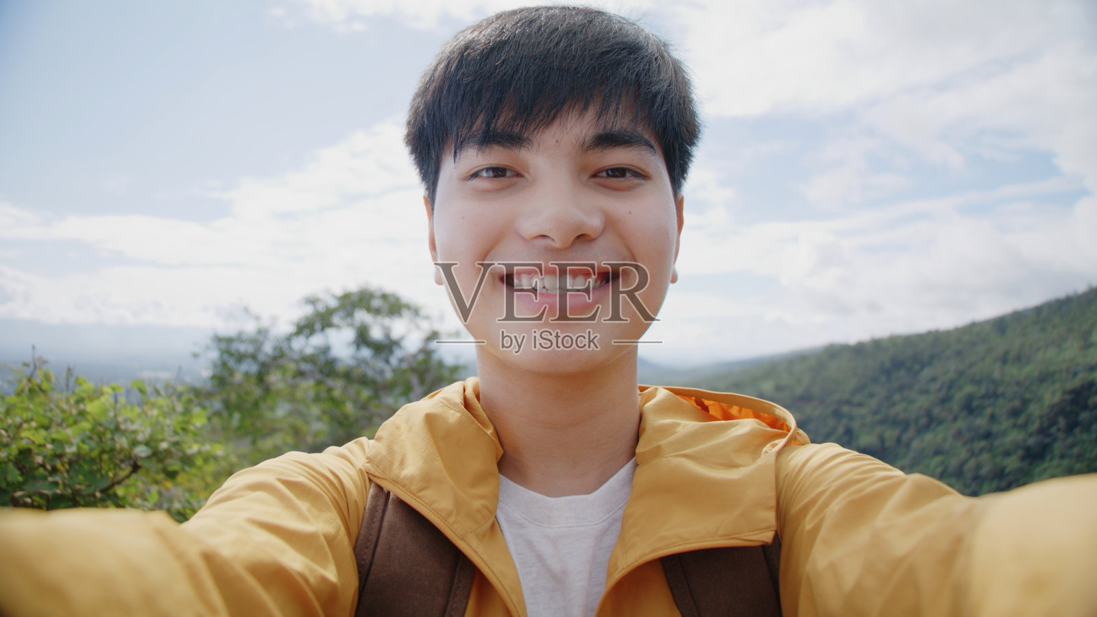 在山区背景的旅游少年拿着智能手机照片摄影图片