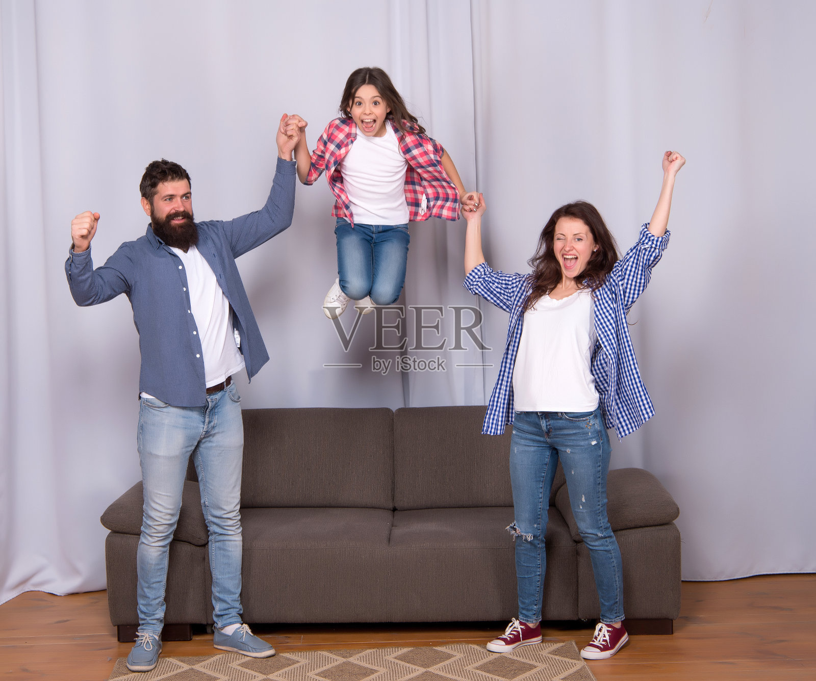 快乐的一家：妈妈、爸爸和女儿在沙发上放松照片摄影图片