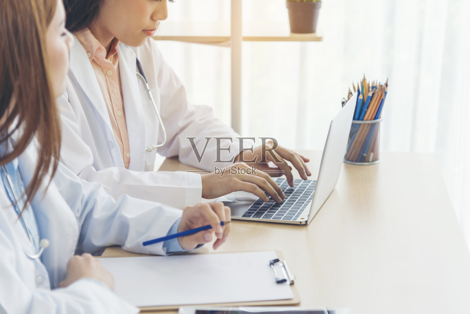 两个亚洲女医生讨论会议医生办公室医疗诊所使用笔记本电脑咨询病人的疾病。亚洲医学实验室的年轻女性在一起讨论医疗互助团队照片摄影图片