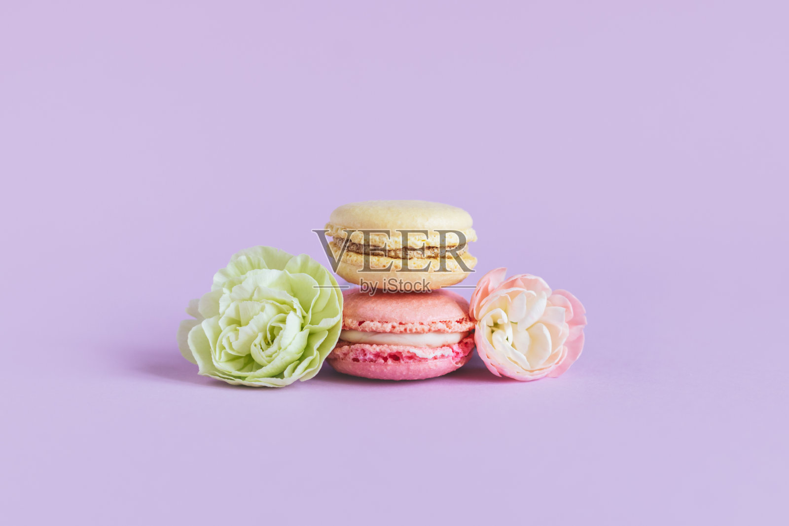 美味的法式马卡龙与温柔的花朵紫色柔和的背景。照片摄影图片