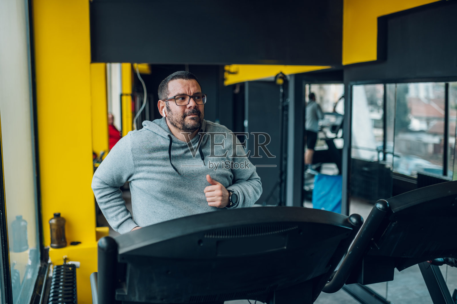 一个中年人在健身房的跑步机上跑步照片摄影图片