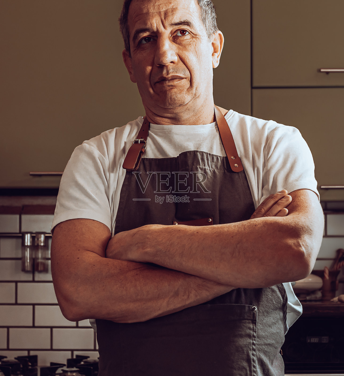 肌肉发达的男人站在厨房里，做面团的材料放在桌子上照片摄影图片