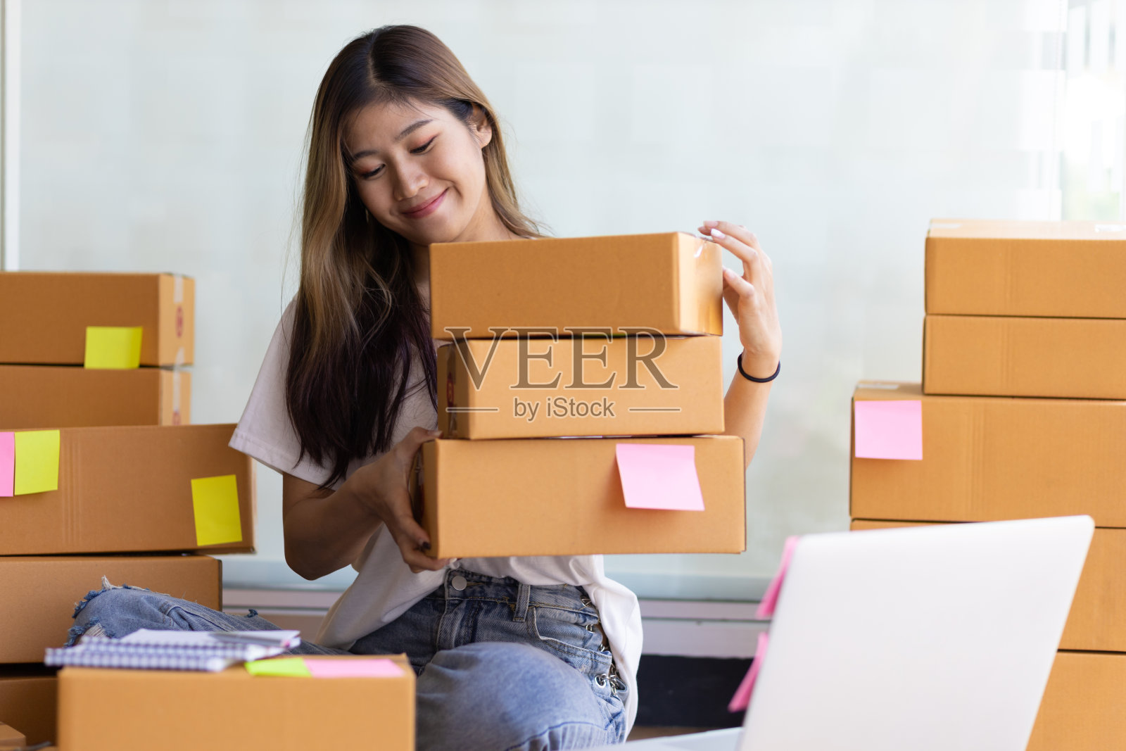一个亚洲女孩在网上做小生意，准备货物送包裹。照片摄影图片