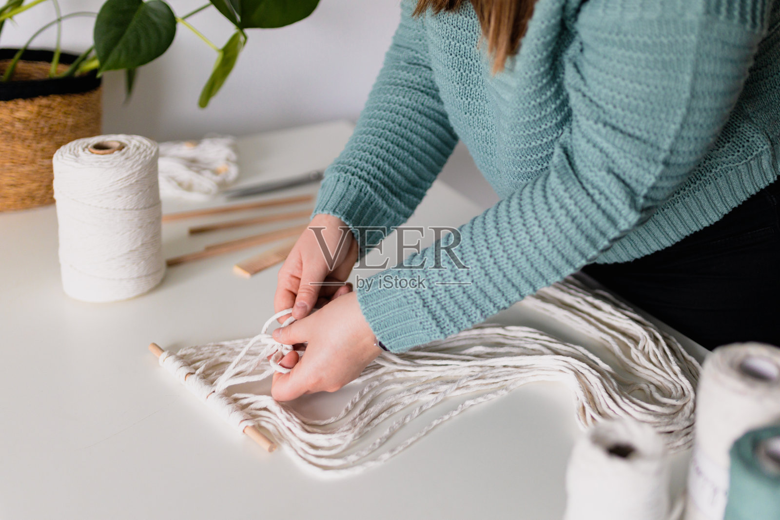 女人做流苏时的手。天然棉线和木珠。手工编织腰带在工作过程中。女性的爱好。照片摄影图片