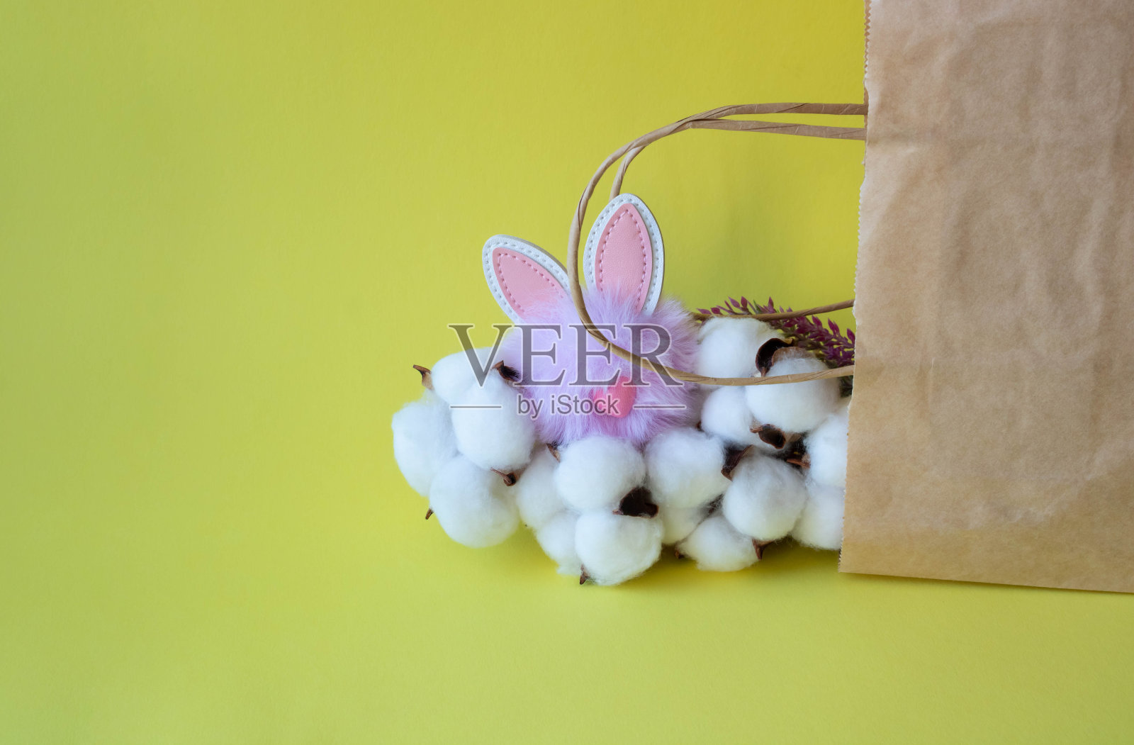 有机环保纸袋棉花和一个可爱的紫色兔子在黄色的背景。零浪费，环保理念。复活节的概念。放置文本照片摄影图片