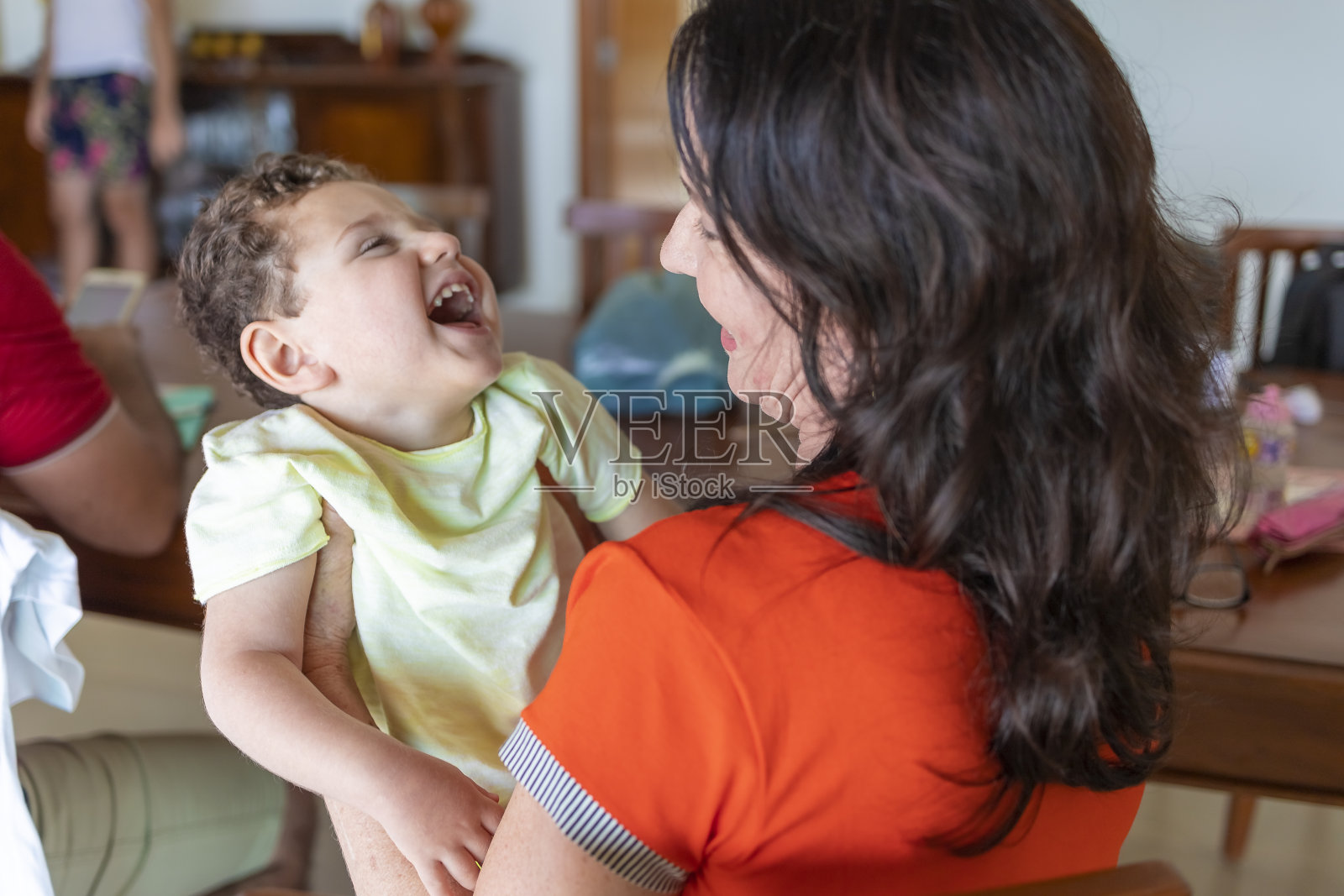 有特殊需要的孩子对母亲微笑，目光狭隘照片摄影图片