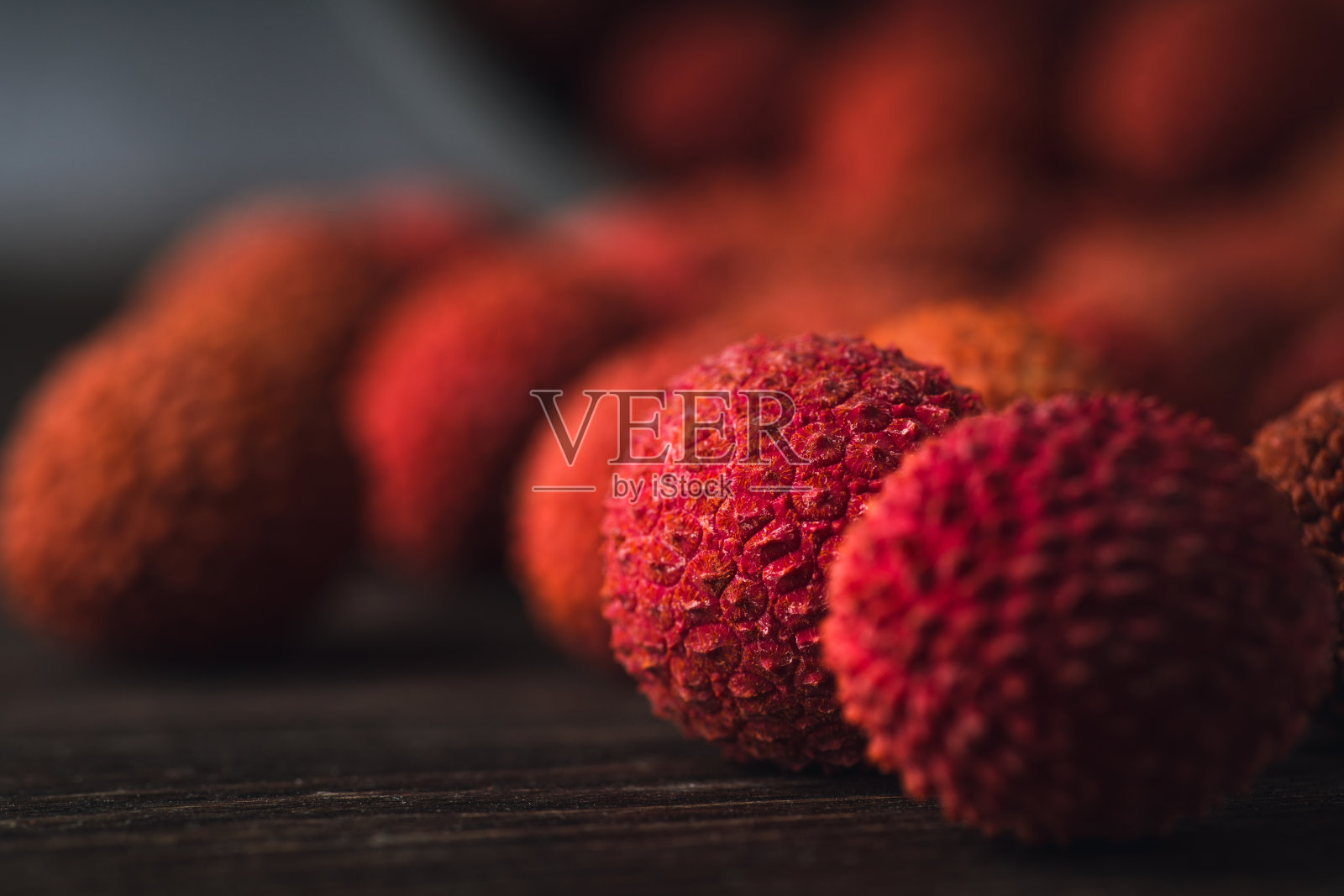 木桌上放着熟透的红色荔枝。有选择性的重点。浅景深。照片摄影图片