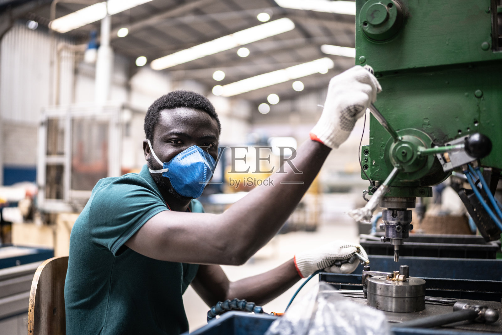 一名年轻男子在工厂/工业中工作——戴着口罩照片摄影图片