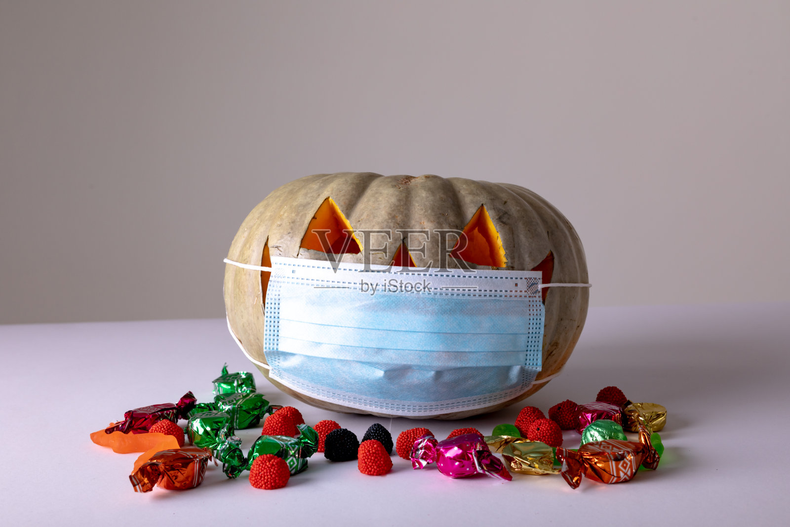 万圣节南瓜灯与面具在灰色背景与糖果照片摄影图片