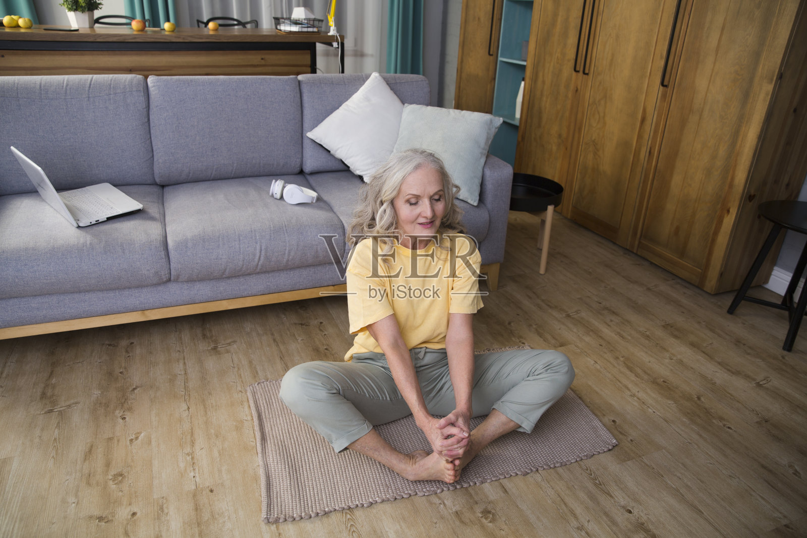 一位老妇人正在家里做伸展运动或瑜伽。健康的生活方式。在家运动照片摄影图片