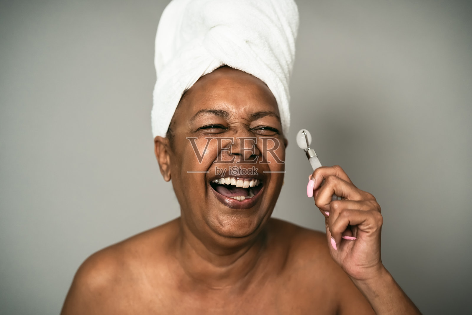 快乐的非洲发型女性在使用玉石滚轮护肤水疗日-人的健康生活方式的概念照片摄影图片