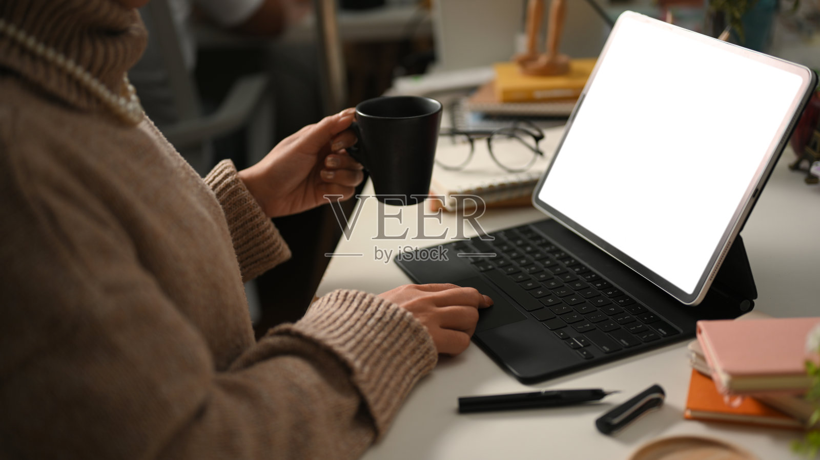 女性自由职业者一边喝着热咖啡，一边在她的便携式平板电脑上工作照片摄影图片