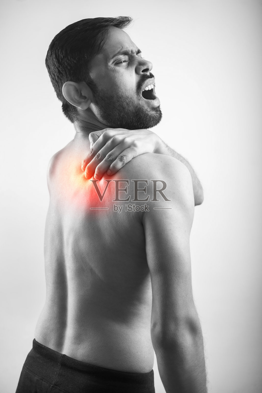 男子抱着肩胛骨痛点用红色高光辉映照片摄影图片