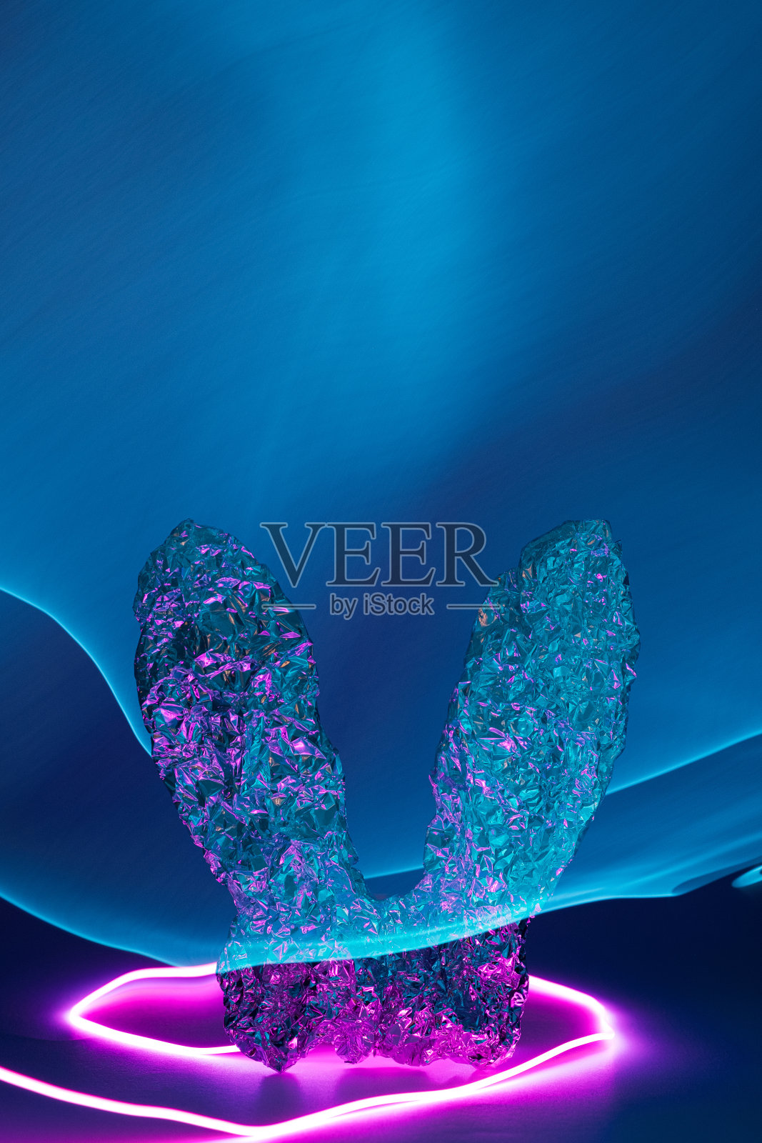 复活节兔子的铝箔耳朵上有粉色和蓝色的霓虹灯。照片摄影图片