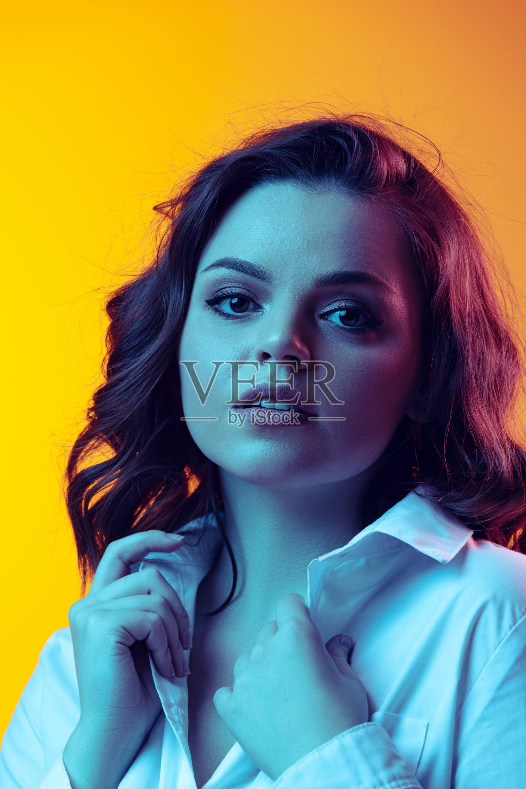 年轻美丽的女孩的肖像与长卷发摆孤立在橙色背景霓虹灯，滤镜。情感、美、时尚的概念照片摄影图片