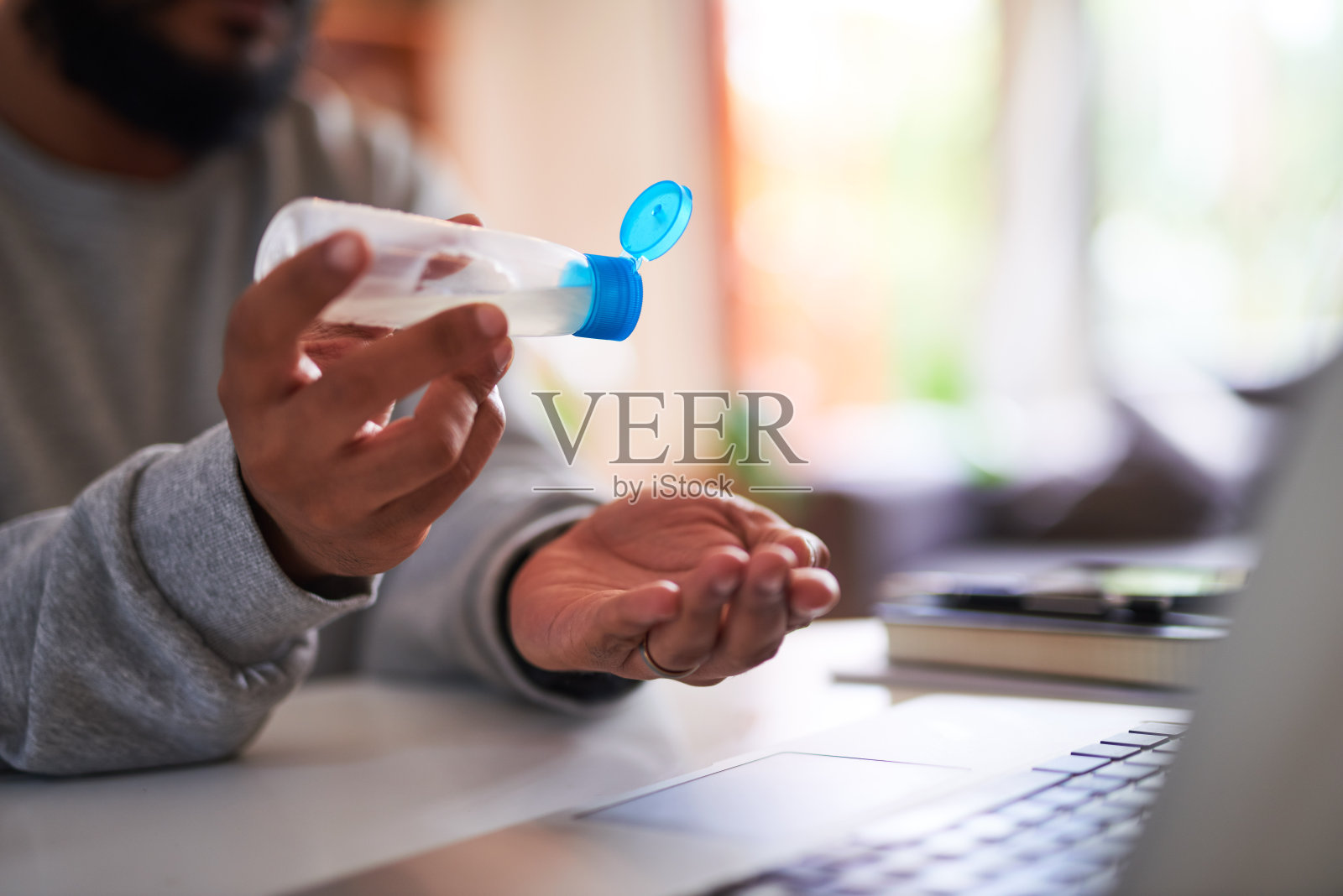 一名男子在办公室里把洗手液倒在手上以保持双手清洁照片摄影图片