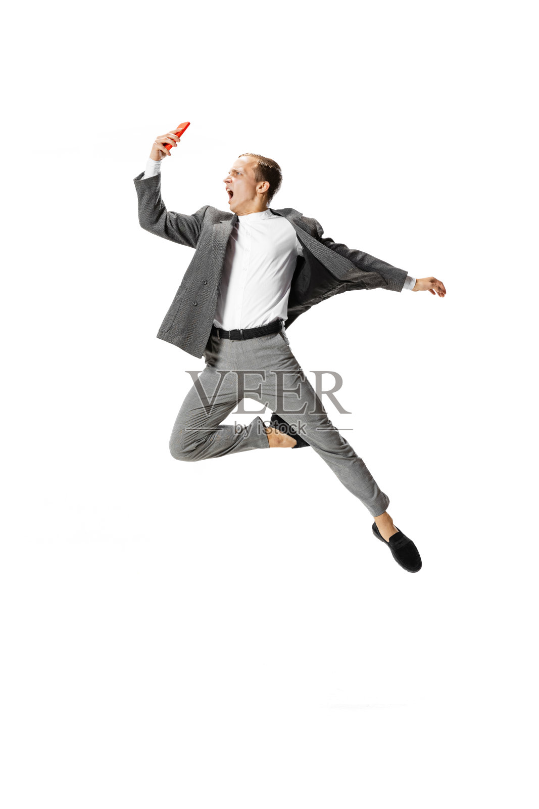 一个穿着灰色西装的年轻人在白色的背景上跳舞、跳跃、飞翔。商业，艺术，运动，行动，创意，灵感的概念。照片摄影图片