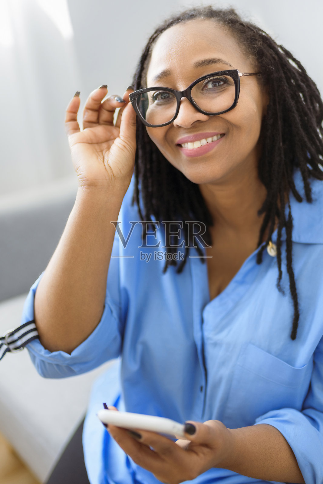 一名非洲妇女坐在沙发上拿着手机照片摄影图片