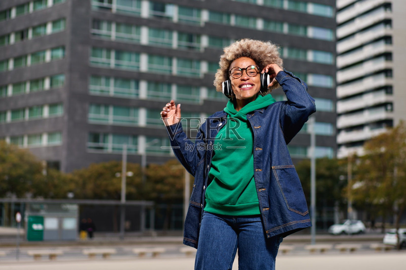 年轻迷人的黑人女孩的肖像在城市背景听音乐与耳机照片摄影图片