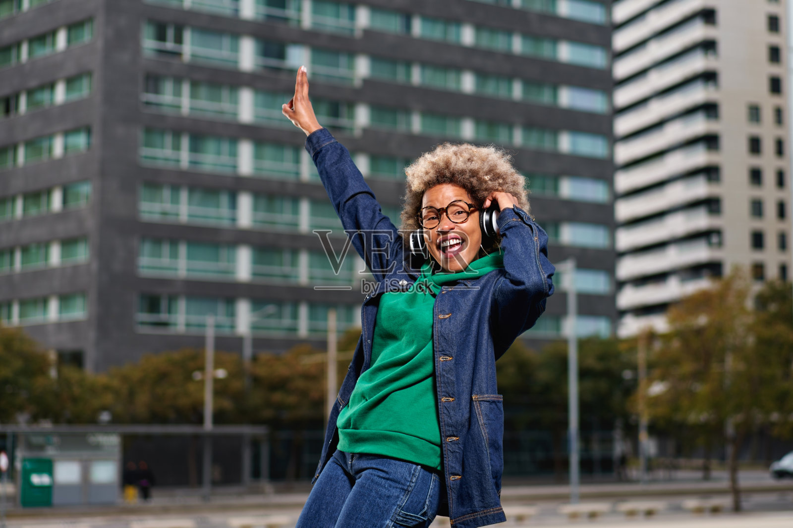 在城市背景下，留着非洲式发型的非裔美国妇女微笑着。穿着休闲服装的黑人女孩。照片摄影图片