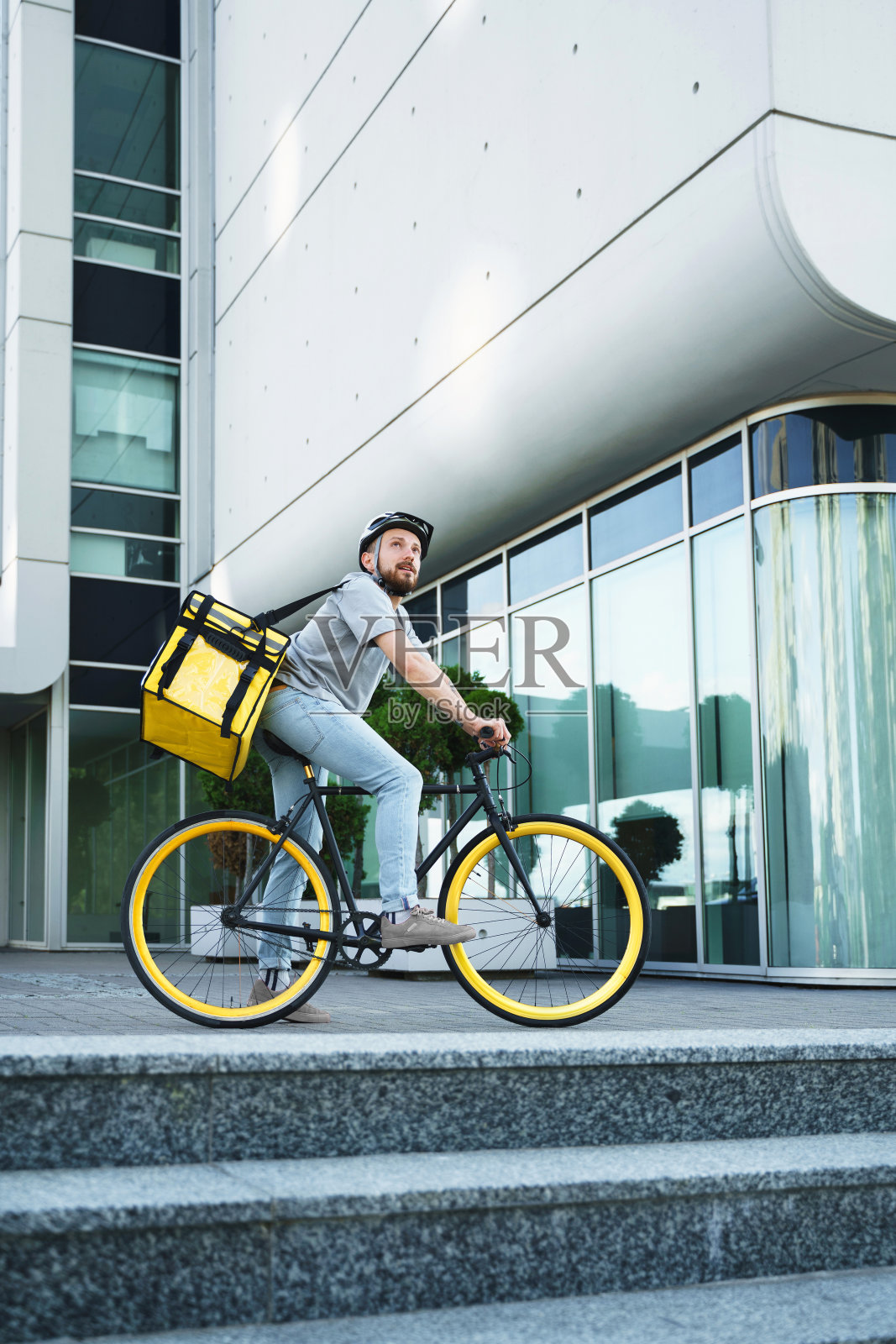 快递员站在自行车上用保温袋。照片摄影图片