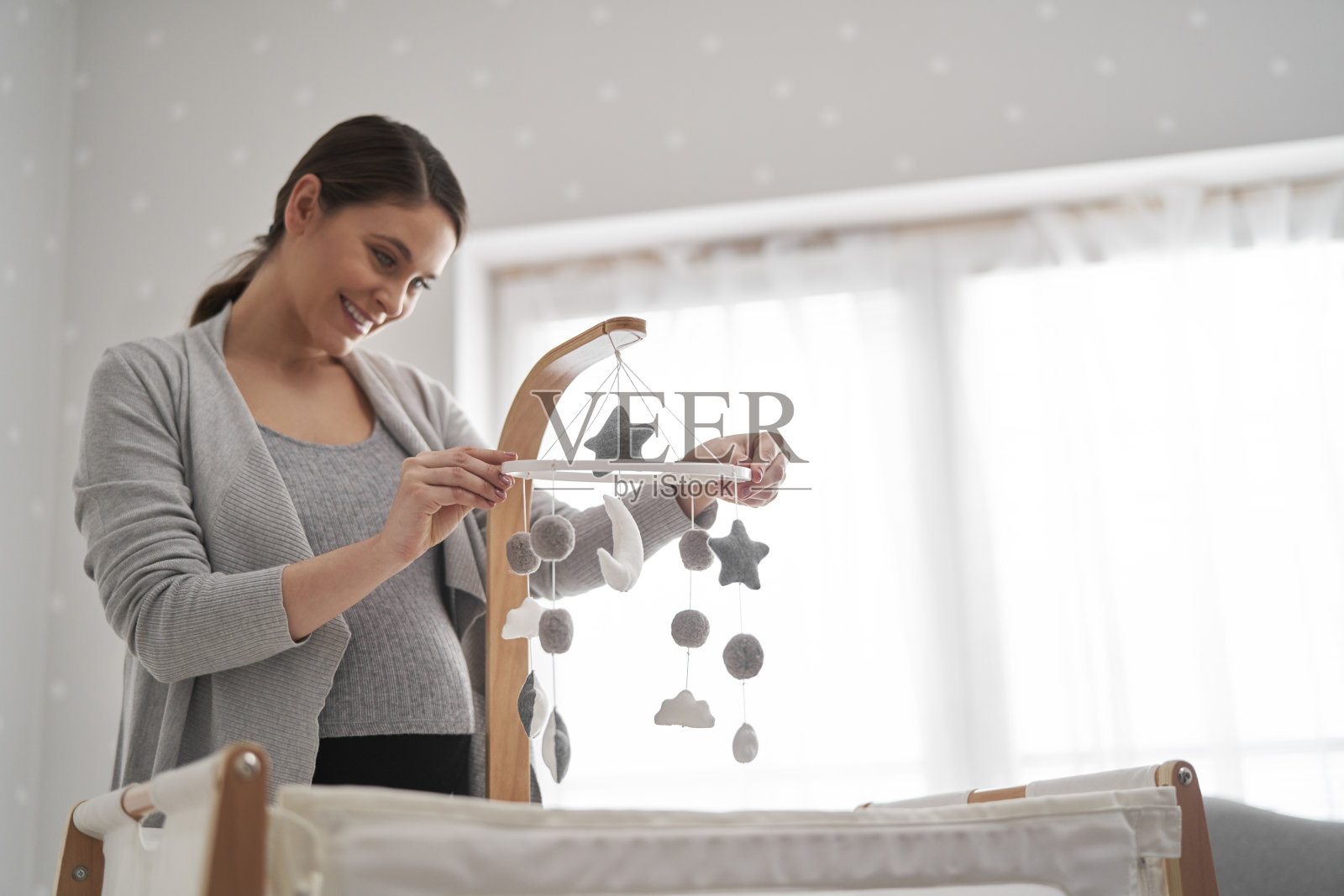 白人孕妇在婴儿床上安装移动玩具照片摄影图片